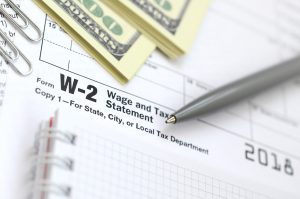 A pen and cash on a W-2