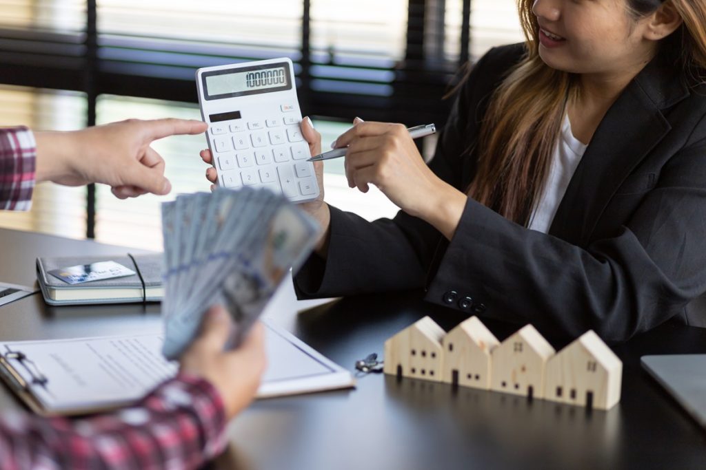 An accountant showing calculations to a client at a table with model houses