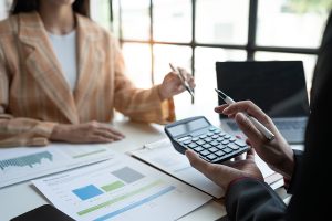 Two professionals in an office with one person holding a calculator.