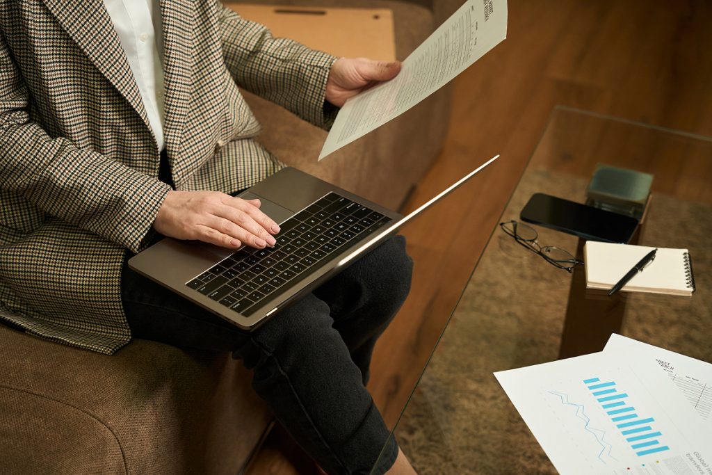 A female professional looking through her laptop and a spreadsheet